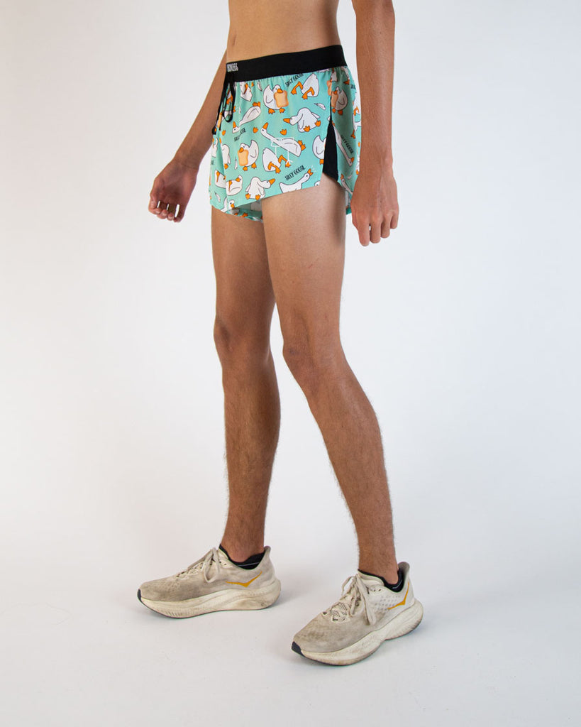 Runner is wearing ChicknLegs in the men's 2 in drawstring split running shorts in the Silly Goose design. White, orange and blue colors are all over with geese holding bread doing silly poses.