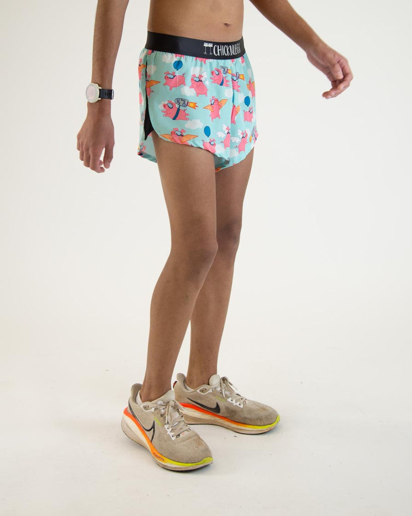 Runner is wearing ChicknLegs in the men's 2 in split running shorts in the flying pigs design. The print has pink piggies on it with goggles, cardboard, wings, and jetpacks on a baby blue background.