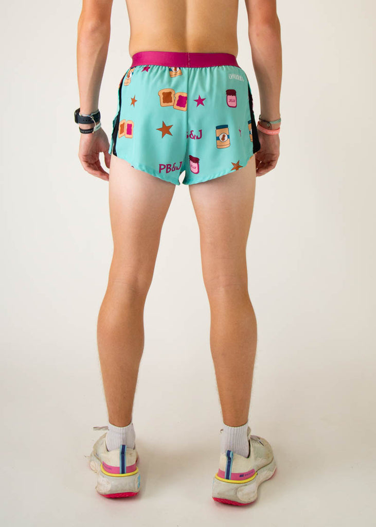 The model is a runner that is wearing athletic Chicknlegs men's 2 inch split running shorts in the PB&J design that includes PB&J sandwiches, peanut butter, jelly on a light blue background, facing away from the camera to see the back of the shorts.
