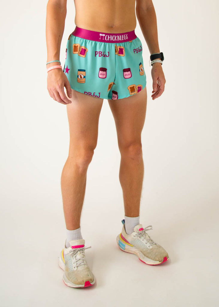 The model is a runner that is wearing athletic Chicknlegs men's 2 inch split running shorts in the PB&J design that includes PB&J sandwiches, peanut butter, jelly on a light blue background, facing right.
