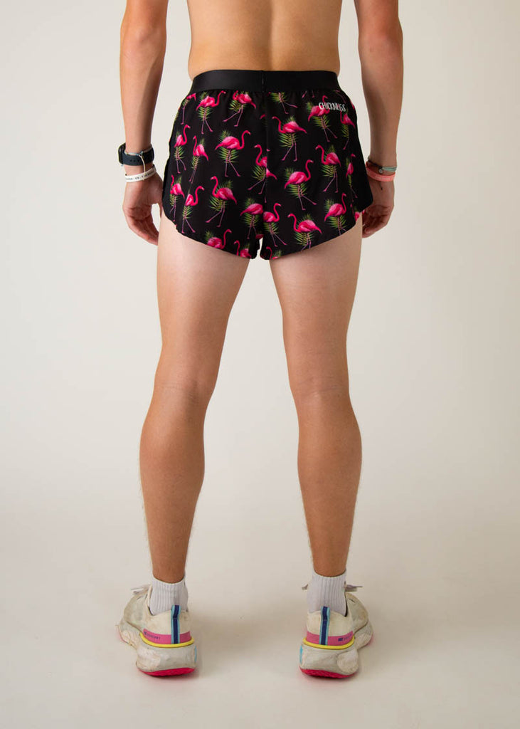 Model is a runner wearing Chicknlegs men's 2 inch split running shorts in the black flamingo design, facing away from the camera to show the back of the shorts.
