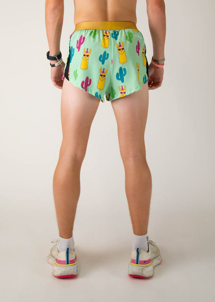 The model is a runner wearing Chicknlegs in men's 2 inch split running shorts in the green llama design, facing away from the camera to see the back of the shorts.
