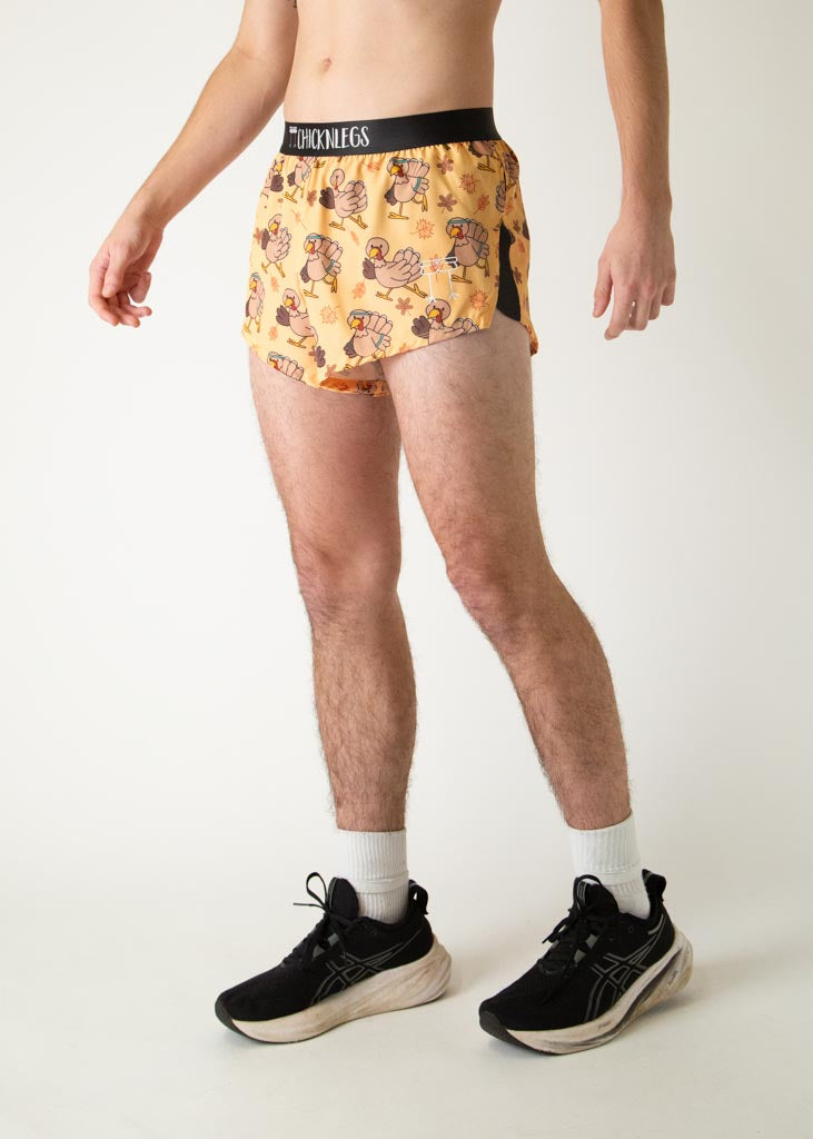 The model is a runner who is wearing Chicknlegs in men's 2 inch split running shorts in the pardoned turkey design, facing left.