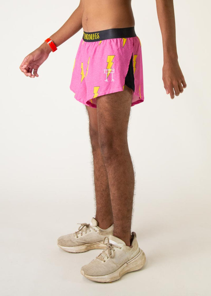 The model is a runner who is wearing Chicknlegs men's 2 inch split running shorts in the pink bolts design, facing left.