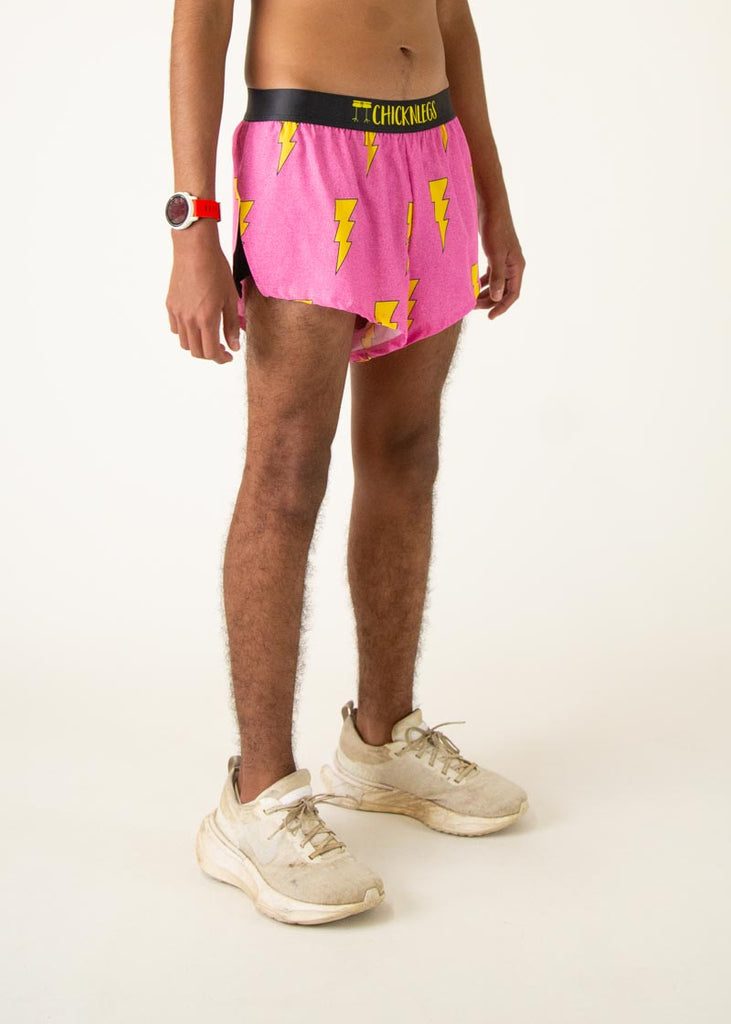 The model is a runner who is wearing Chicknlegs men's 2 inch split running shorts in the pink bolts design, facing right.