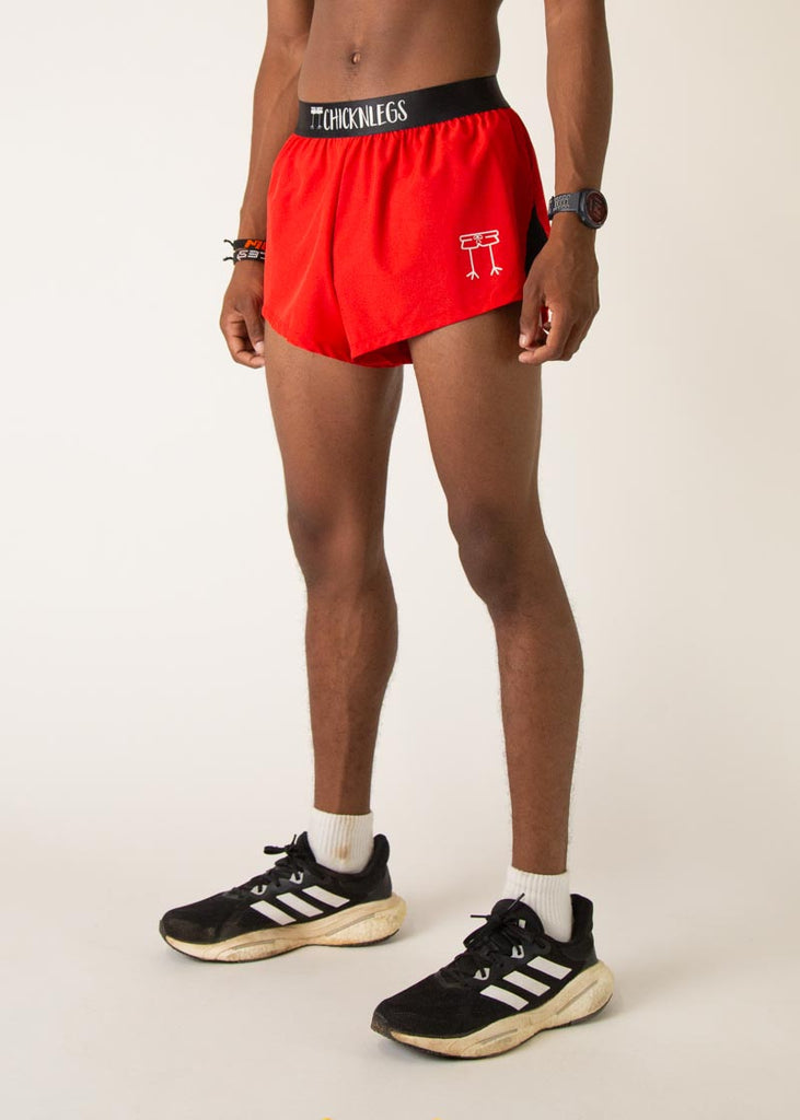 Model is wearing Chicknlegs mens 2 inch split running shorts in the red design, facing left.