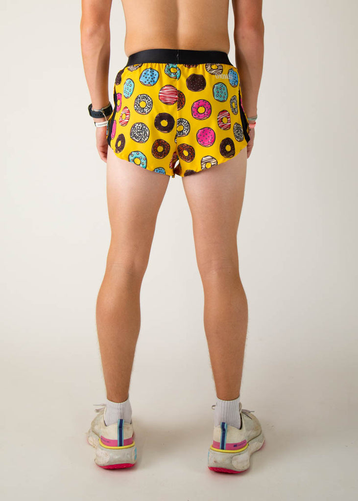 The model is a runner that is wearing Chicknlegs men's 2 inch split running shorts in the salty donuts design, facing away from the camera to show the shorts.

