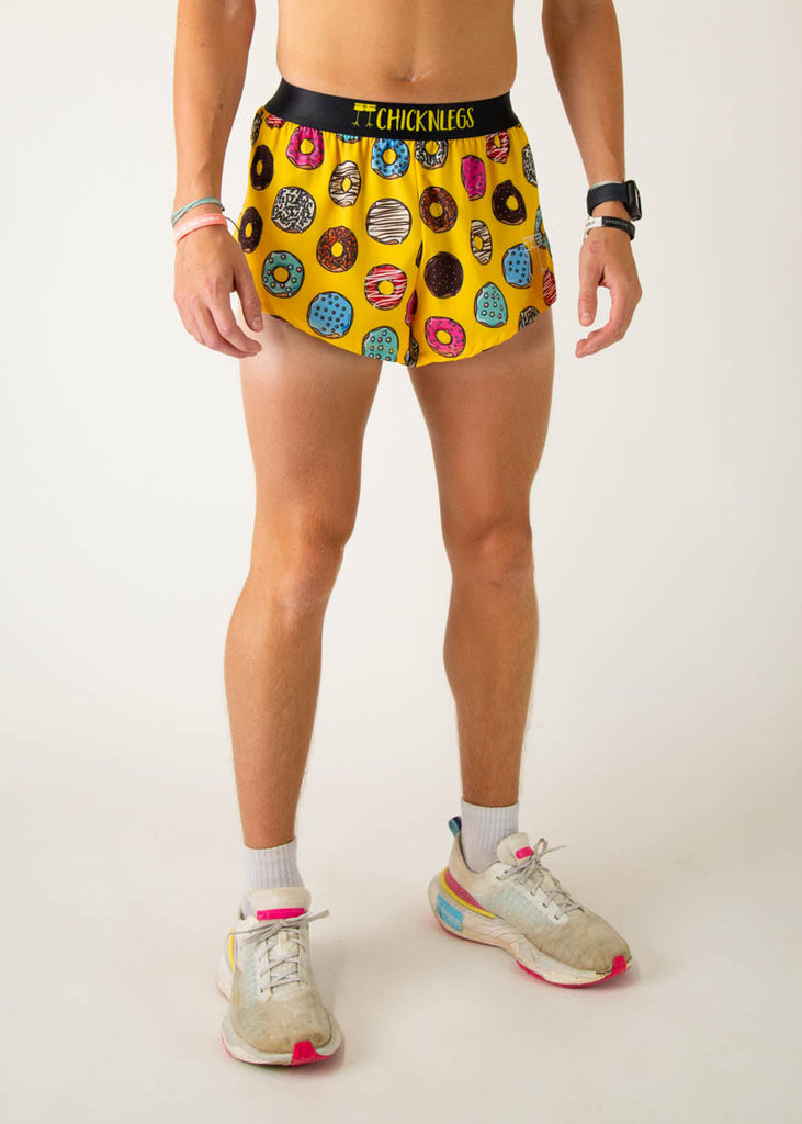 The model is a runner that is wearing Chicknlegs men's 2 inch split running shorts in the salty donuts design, facing right.