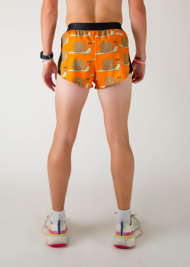 The model is a runner wearing Chicknleg's men's 2 inch split running shorts in the snails design, facing away from the camera to show the back view of the shorts.
