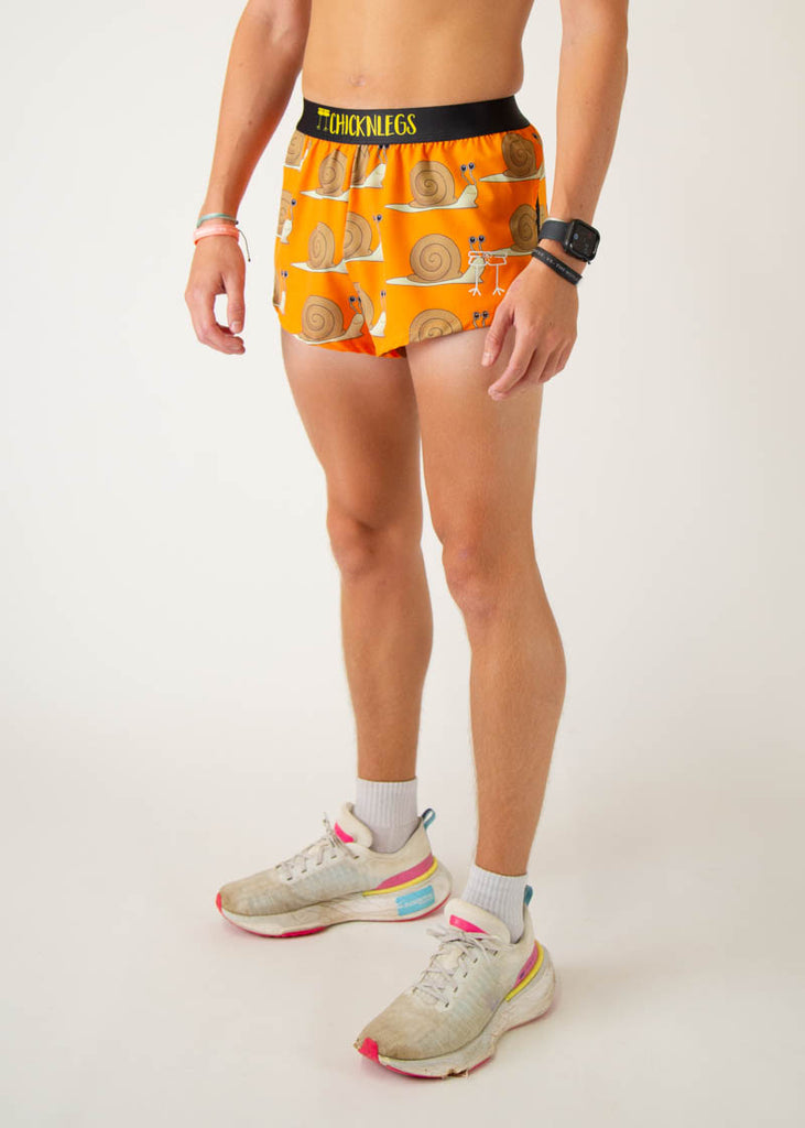 The model is a runner wearing Chicknleg's men's 2 inch split running shorts in the snails design, facing left.
