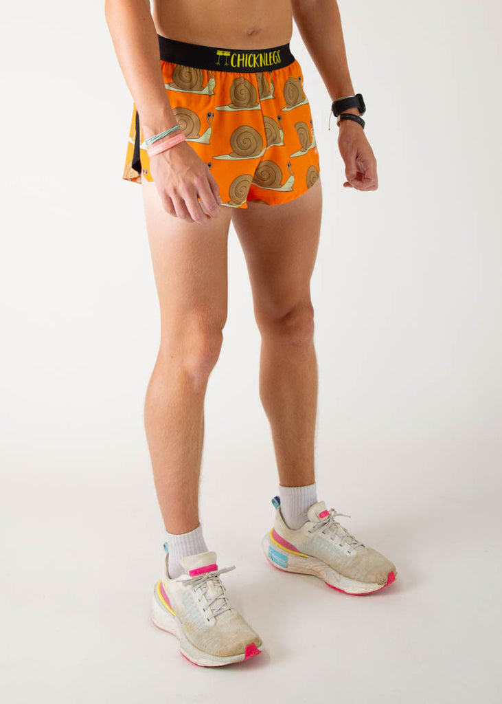The model is a runner wearing Chicknleg's men's 2 inch split running shorts in the snails design, facing right.
