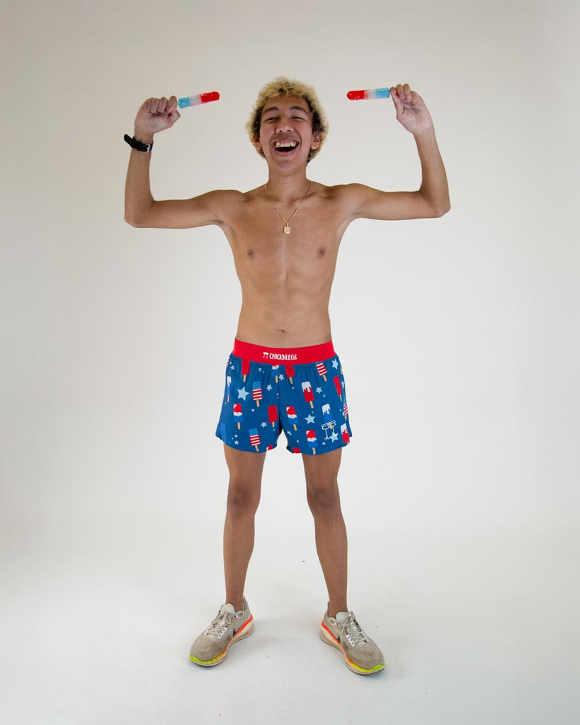 Runner is wearing ChicknLegs in the men's 4 in split running shorts with the USA popsicle design. The print has red, white and blue ice cream and white and blue stars on it with a red waistband, posing with ice cream and screaming for american pride and 4th of july.
