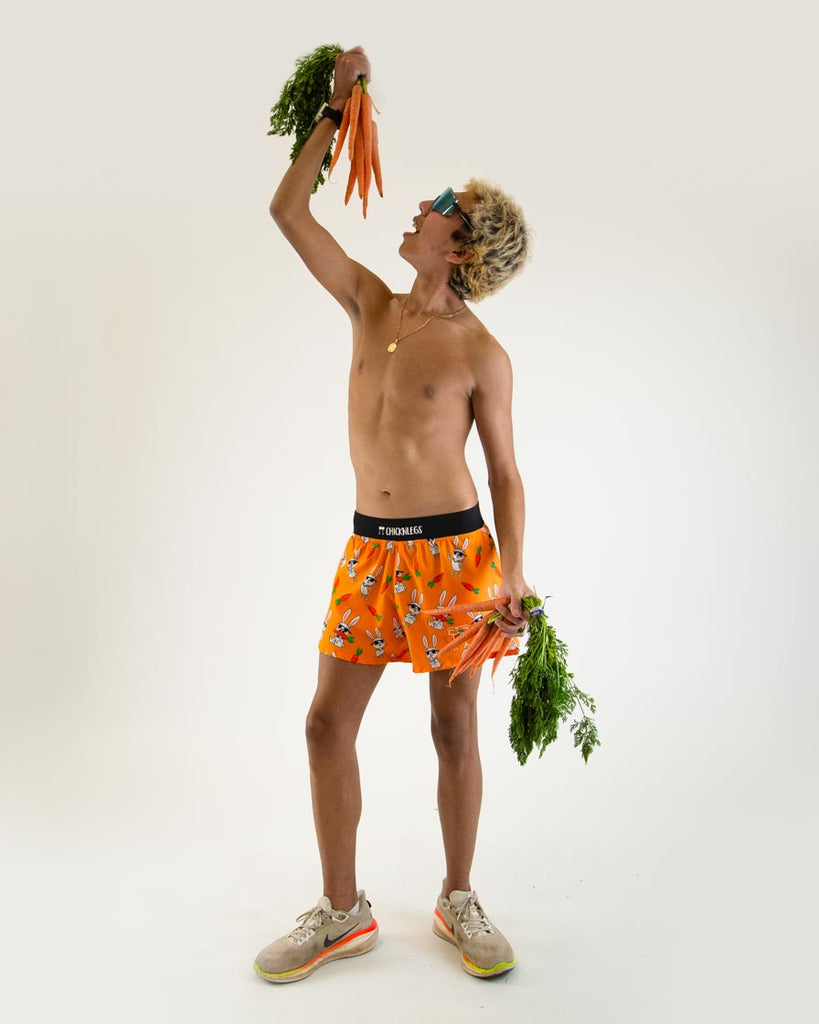 Runner is wearing ChicknLegs in the men's 4 in split running shorts in the bad bunny design, facing front. The print has white hare on it for how fast they are with muscles on an orange background. 