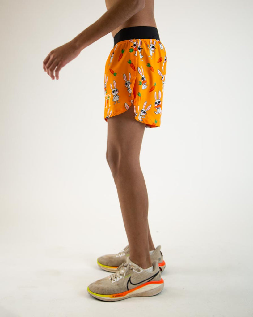 Runner is wearing ChicknLegs in the men's 4 in split running shorts in the bad bunny design, facing left. The print has white hares  on it with sunglasses and carrots on an orange background.