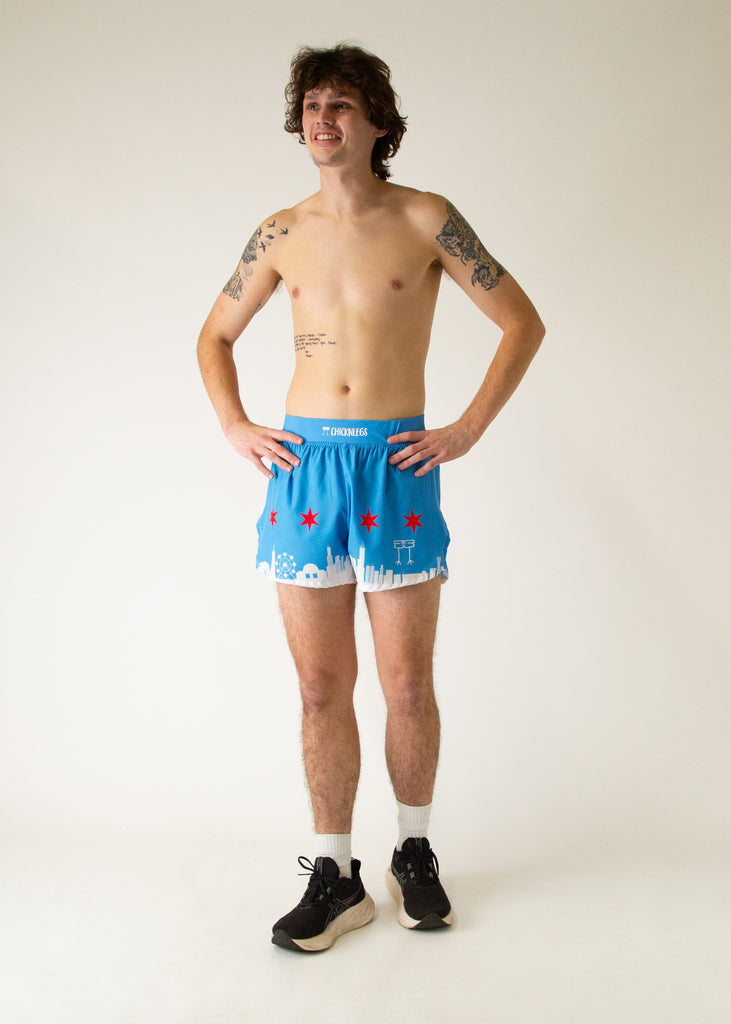 Runner is wearing ChicknLegs in the men's 4 in split running shorts that has the Chicago Style Skylines on it with a white city and blue background with red stars. Full body image is shown of the runner in a walking pose.