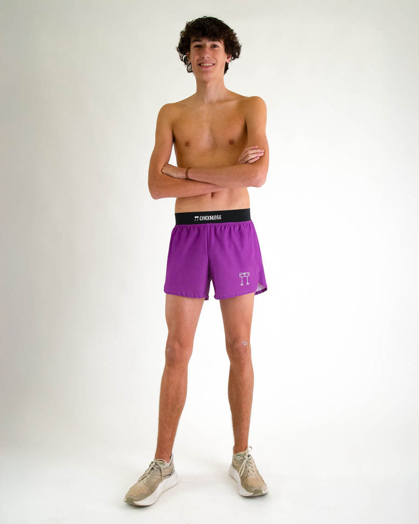 Runner is wearing ChicknLegs in the men's 4 in split running shorts with a back zipper pocket in the deep purple color facing front while posing and crossing their arms. Great length for runners who want more lifestyle and outdoor trail running.