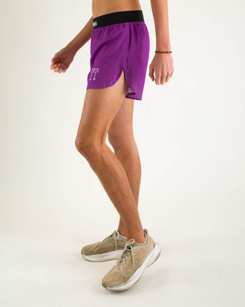 Runner is wearing ChicknLegs in the men's 4 in split running shorts with a back zipper pocket in the deep purple color facing left to show the split short.