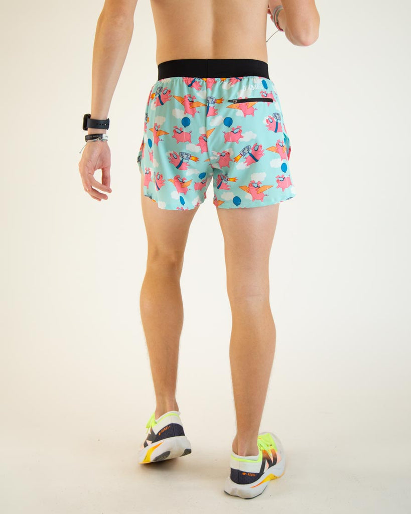Runner is wearing ChicknLegs in the men's 4 in split running shorts in the flying pigs design, facing away from the camera to show the back zipper pocket. The print has pink flying pig on it with clouds, balloons, cardboard wings, and a jetpack.