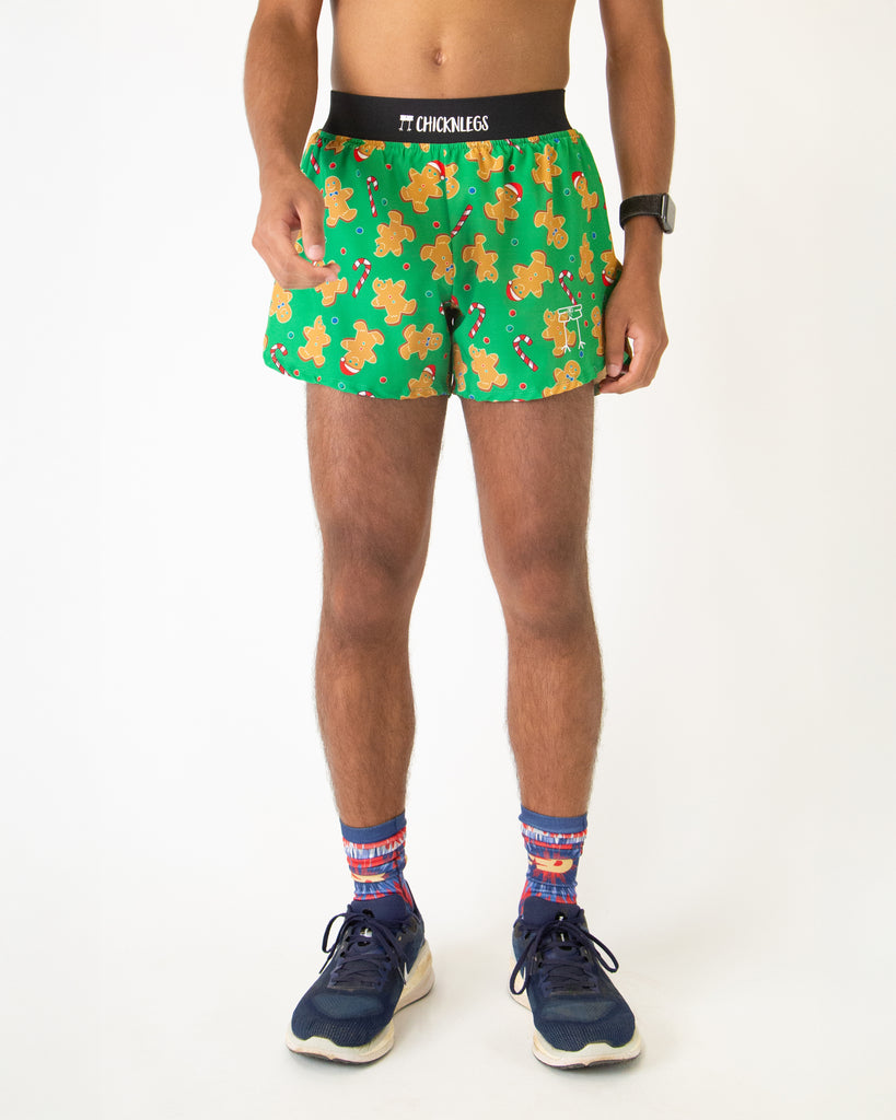 Runner is wearing Chicknlegs in the men's 4 in split running shorts in the gingy's revenge design. The print has gingerbread on it with candy canes in brown, white, green, red, and blue colors.