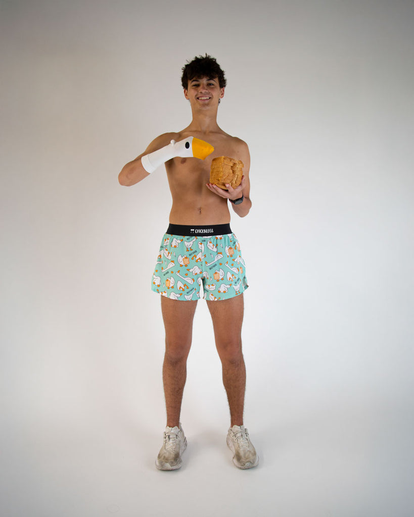 Runner is wearing ChicknLegs in the men's 4 inch split running shorts in the Silly Goose Design. Athlete is posing with loaf of bread slices for a silly type of mood.