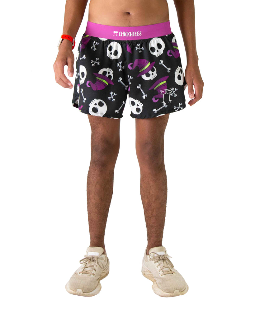 Runner is wearing ChicknLegs in the men's 4 in split running shorts in the skulls design. The print has skeleton skulls on it with bones and witch hats that are in white, purple and green on a black background.