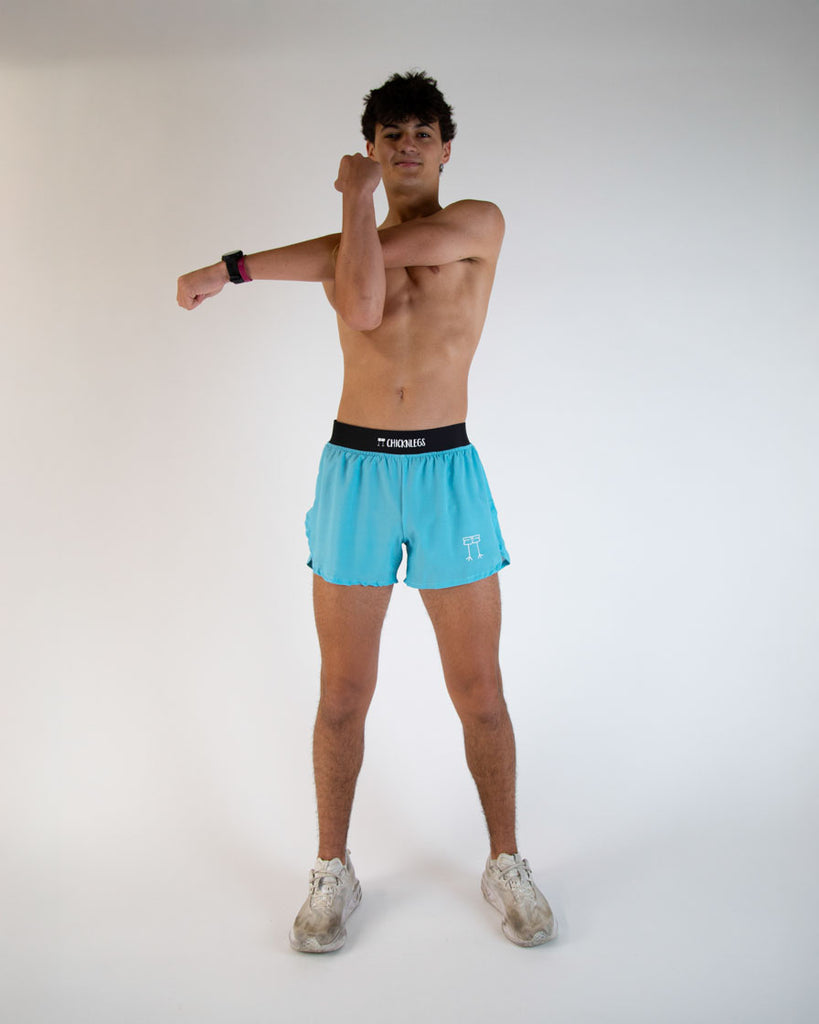 Runner is wearing ChicknLegs in the men's 4 in split running shorts in the sky blue design. Model is stretching to show the flexibility of the shorts.