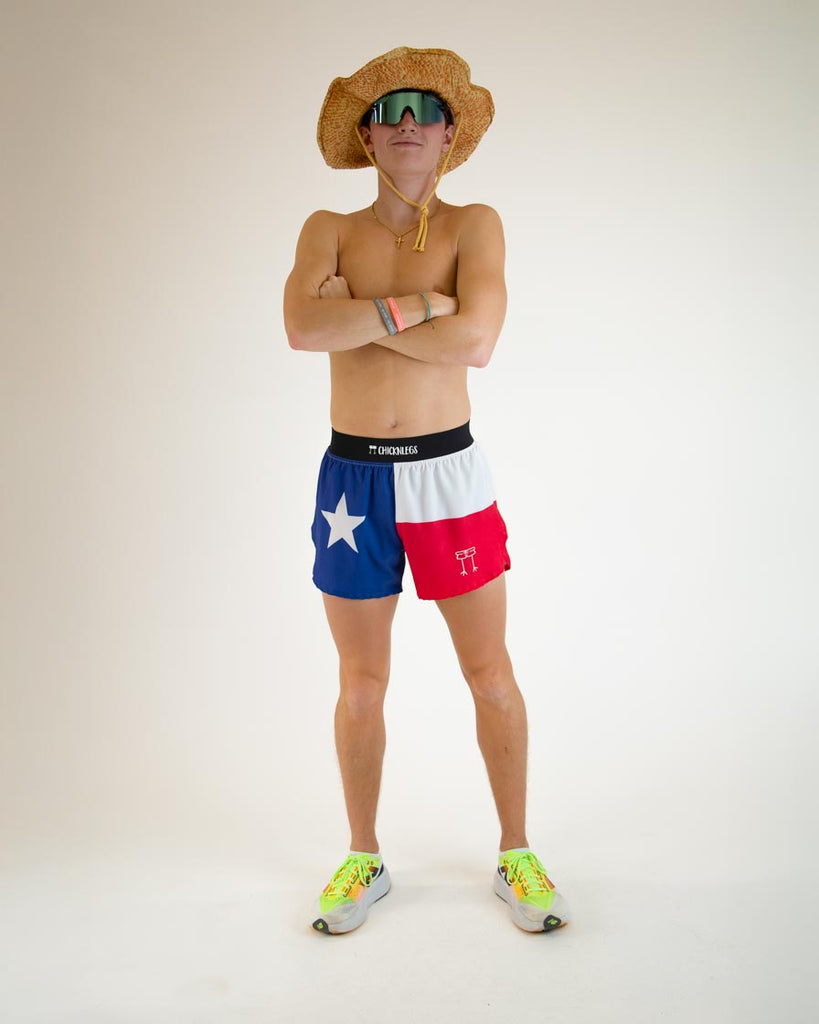 Runner is wearing ChicknLegs in the men's 4 in split running shorts in the Texas Flag design, posing with a cowboy hat and sunglasses.
