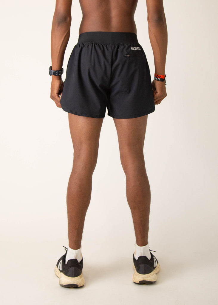 Model wearing Chicknlegs in mens 4 inch split running shorts in the black design, facing away from the camera to show the back view of the shorts.
