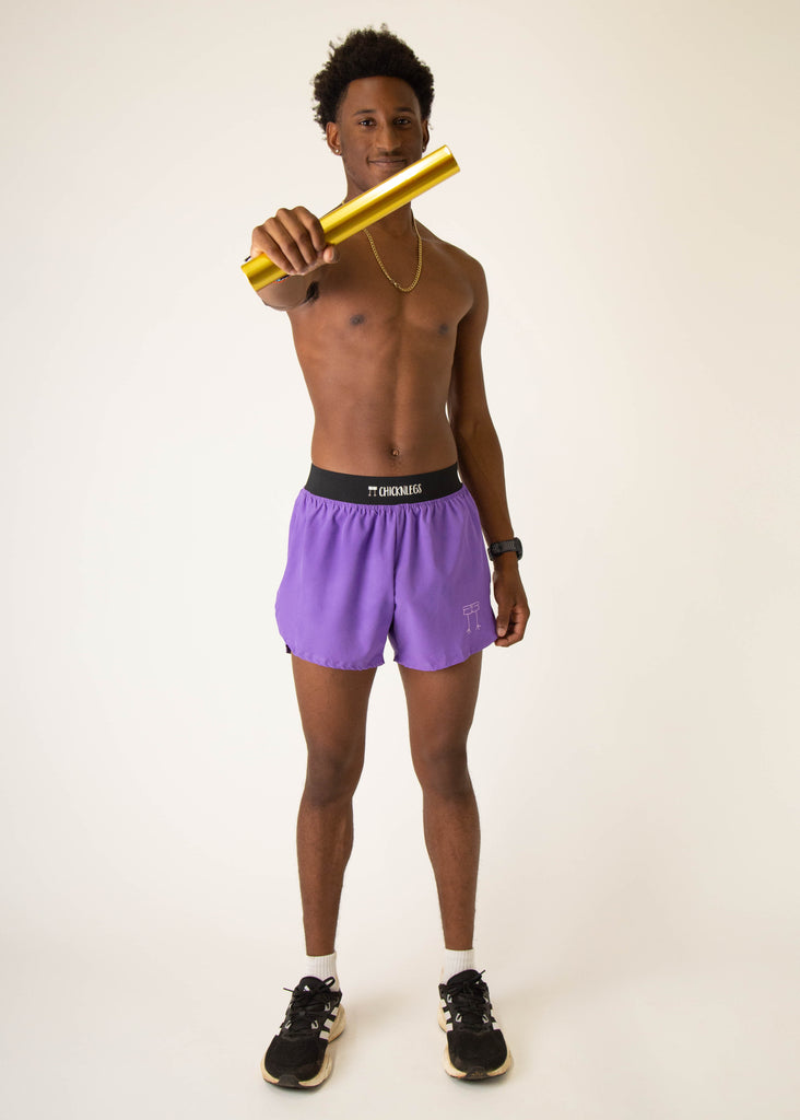 Model wearing Chicknlegs in mens 4 inch split running shorts in the purple design, facing front while posing and holding a baton.
