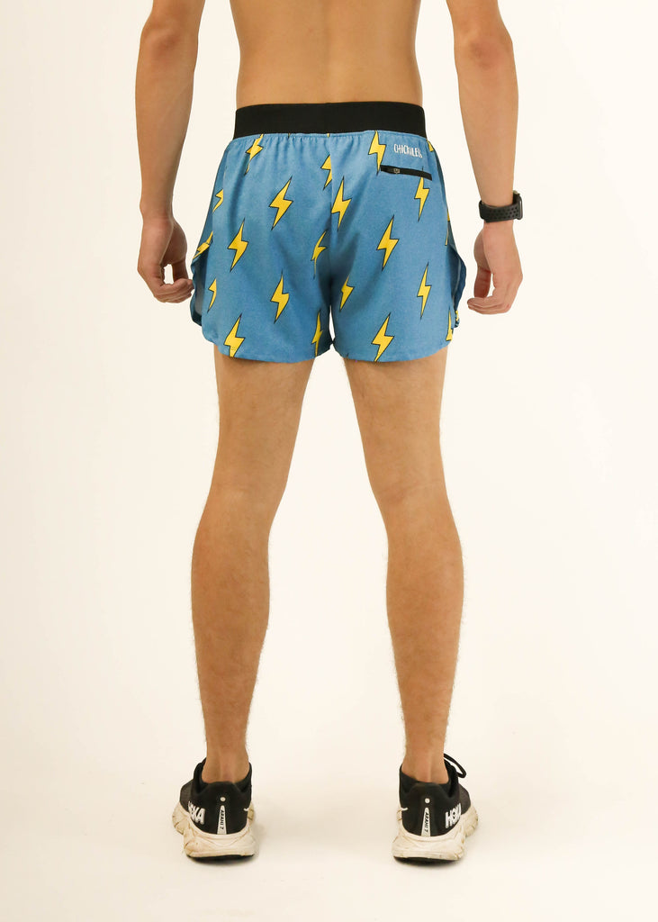 Model wearing Chicknlegs men's 4 inch split running shorts in the blue bolts design facing back for back view.

