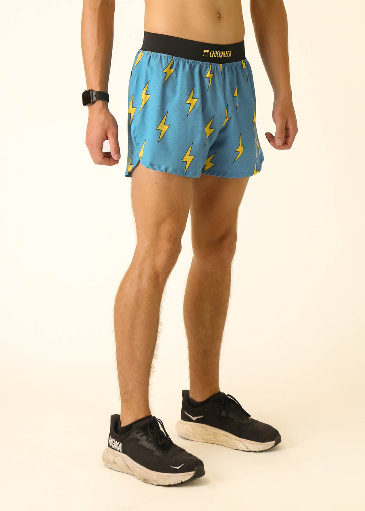 Model wearing Chicknlegs men's 4 inch split running shorts in the blue bolts design facing right side.
