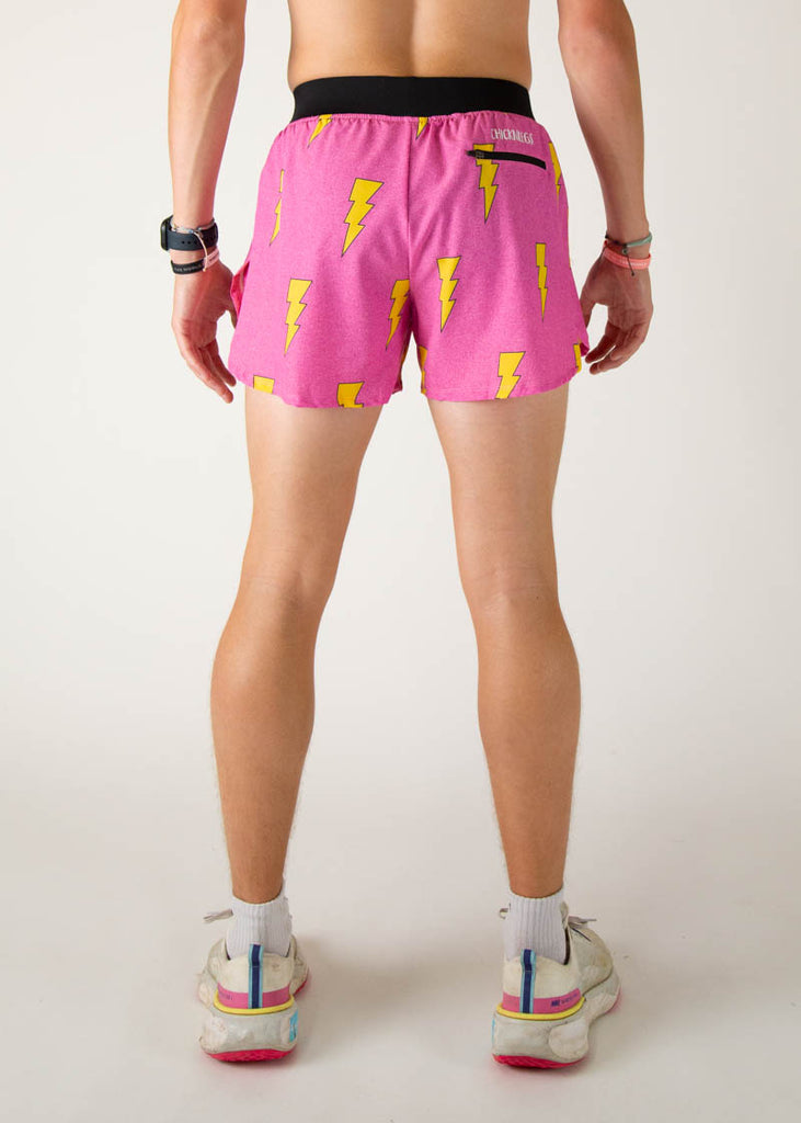 The model is a runner wearing Chicknlegs men's 4 inch split running shorts in the hot pink bolts design, facing away from the camera to show the back of the shorts.
