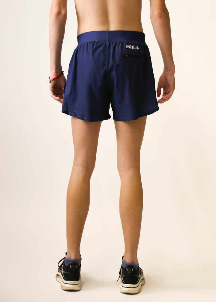 Model is a runner wearing Chicknlegs men's 4 inch split running shorts in the navy blue design facing away from away the camera to show the back of the shorts.