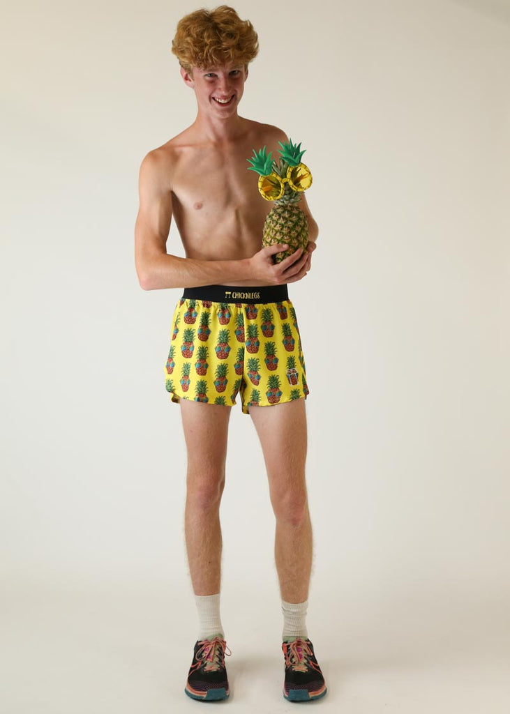 Model wearing Chicknlegs men's 4 inch split running shorts pineapple express design holding a pineapple