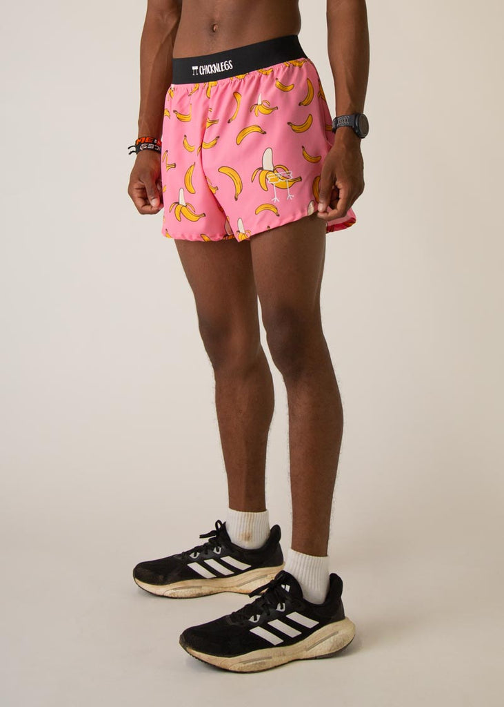 Model wearing Chicknleg's mens 4 inch split running shorts in the pink banana design, facing left.