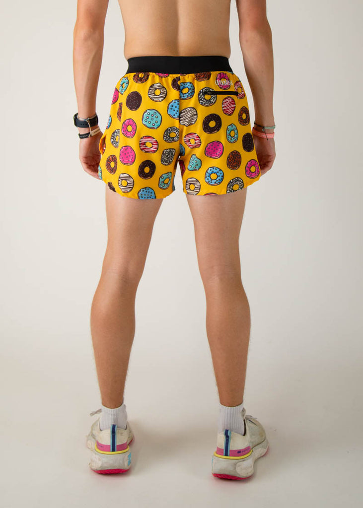 The model is a runner wearing Chicknlegs in the men's 4 inch split running shorts in the salty donuts design, facing away from the camera to show the back of the shorts.
