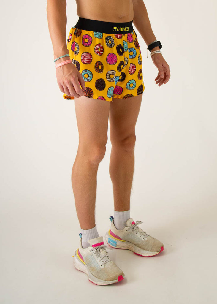 The model is a runner wearing Chicknlegs in the men's 4 inch split running shorts in the salty donuts design, facing right.
