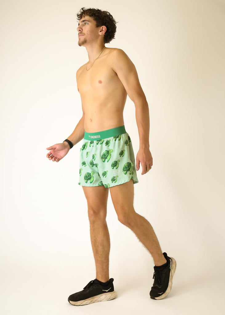 Model is a runner who is wearing Chicknlegs men's 4 inch split running shorts in the turtles design, posing in a walking stance.
