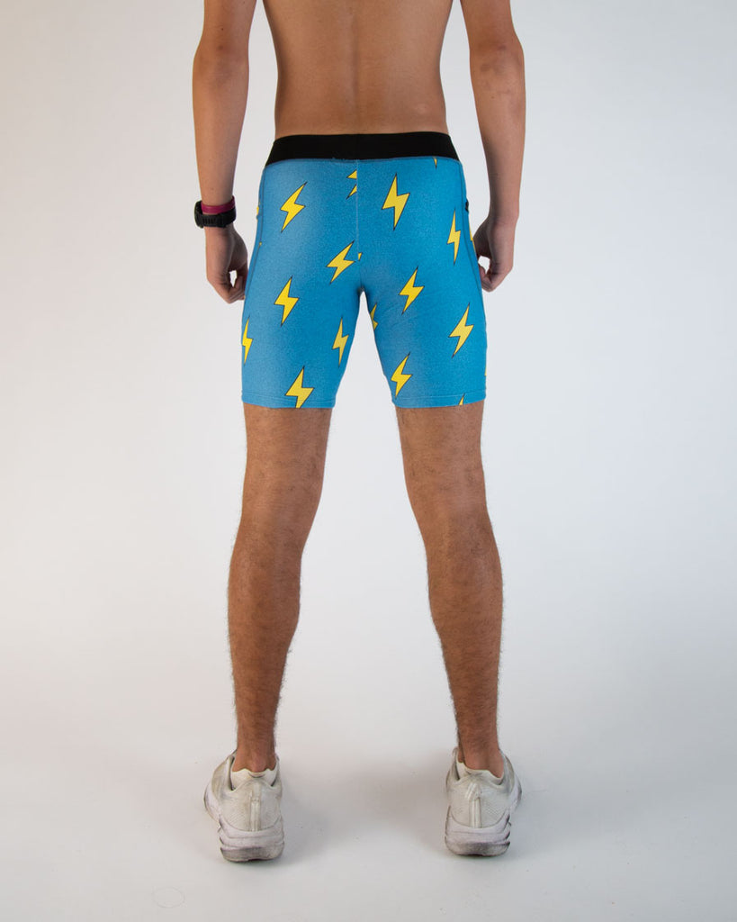 Runner is wearing ChicknLegs in the men's 8 in half tights in the blue bolts design. The print has yellow lightning bolts on a blue background.