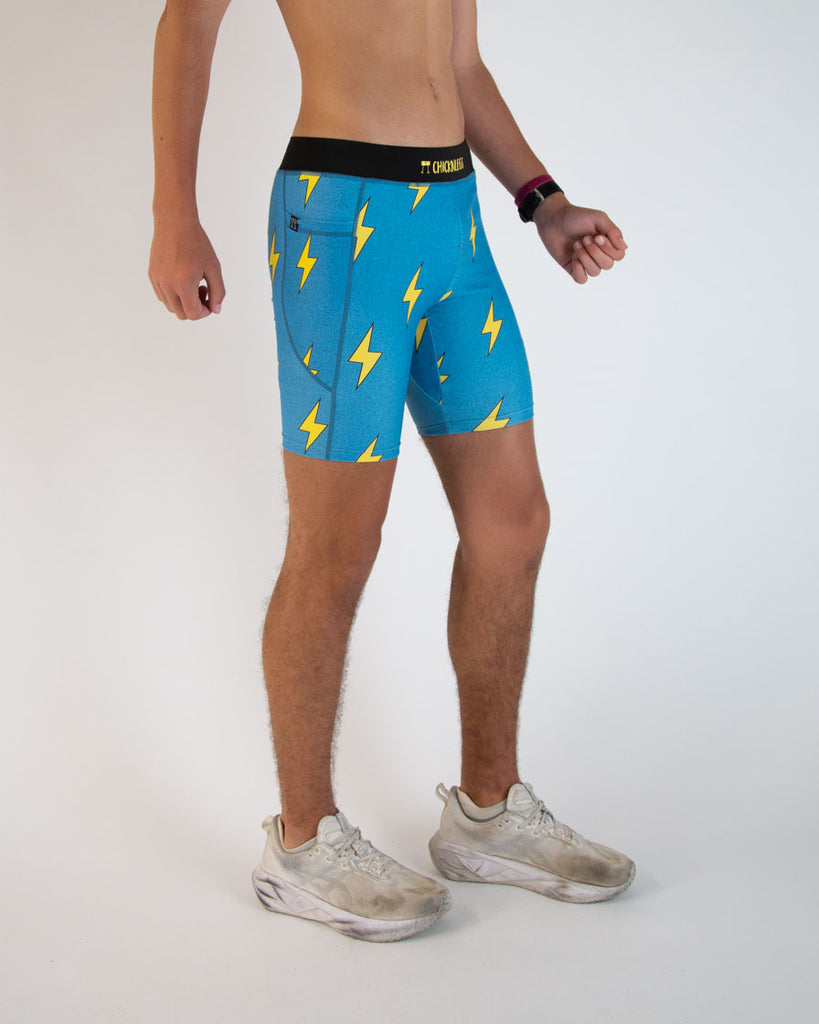 Runner is wearing ChicknLegs in the men's 8 in half tights in the blue bolts design. The print has yellow lightning bolts on a blue background.