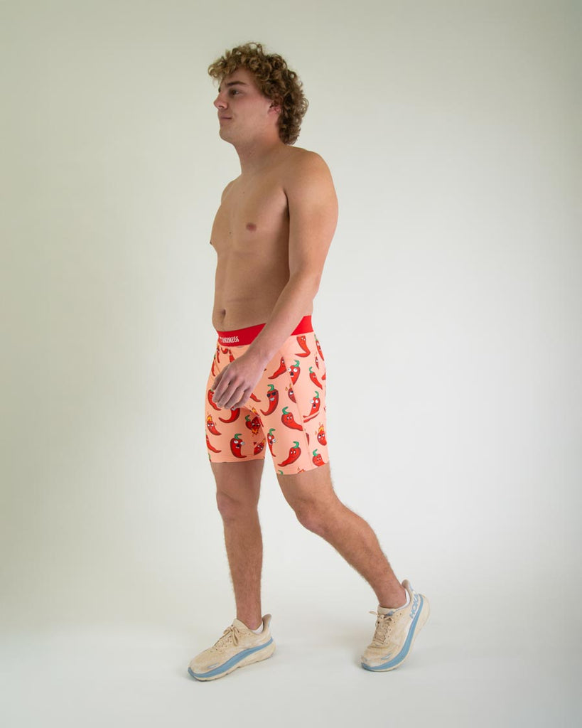 Runner is wearing ChicknLegs in the men's 8 in half tights with pockets in the red hot chili pepper spicy design. The print has red, green and orange on it for a full body view.