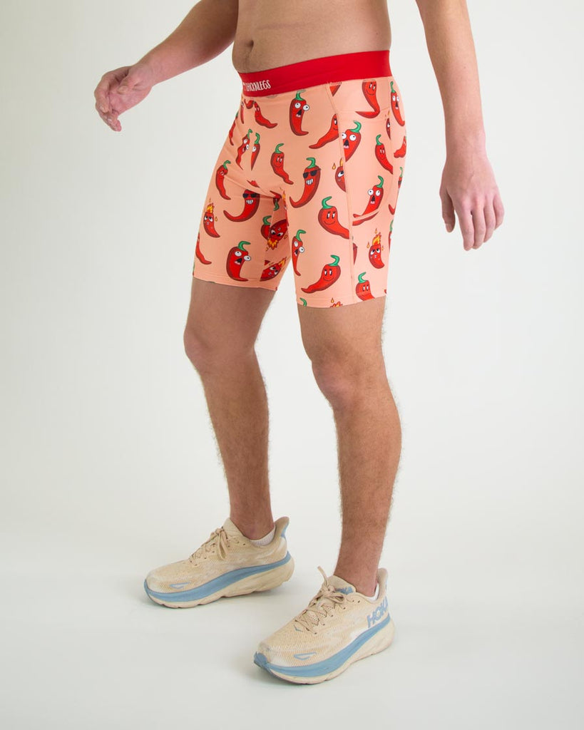 Runner is wearing ChicknLegs in the men's 8 in half tights with pockets in the red hot chili pepper spicy design. The print has red, green and orange on it for left view.