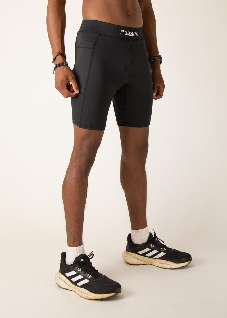 Model wearing Chicknlegs men's 8 inch half tights in the black design, facing right.