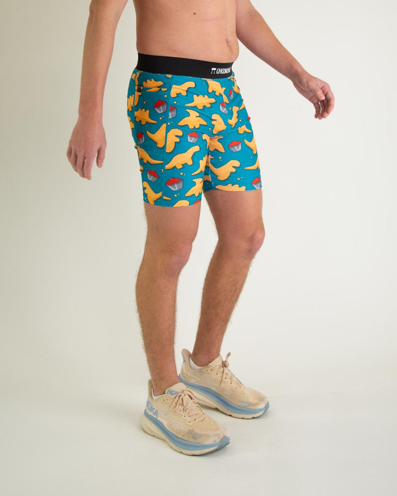 Runner is wearing ChicknLegs in the men's 8 in half tights with pockets in the dino nugget design. The print has chicken dinosaur nuggets on it with ketchup in an orange, red and blue color. A right view of the halftights are shown, great for long distance running and performance to prevent chaffing.  