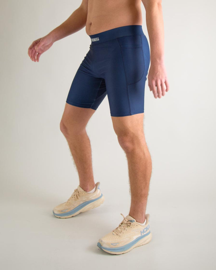 Runner is wearing ChicknLegs in the men's 8 in half tights with pockets in the navy design. The print is a solid navy blue color, great to protect from chaffing and long runs, a left view is shown.