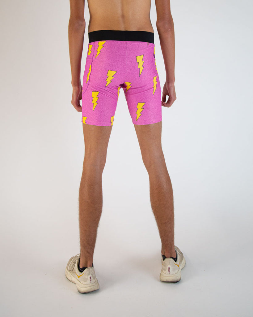 Runner is wearing ChicknLegs in the men's 8 in half tights in the neon hot pink lightning bolts. The print is on bright vibrant pink with yellow bolts.