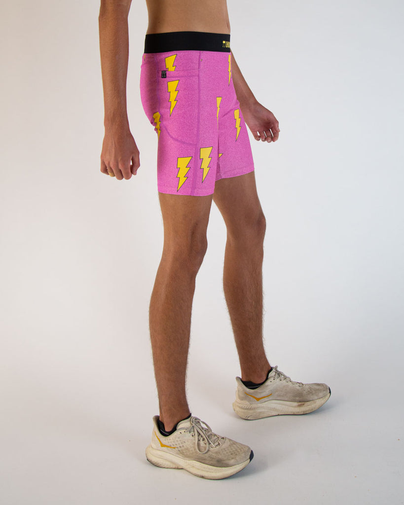 Runner is wearing ChicknLegs in the men's 8 in half tights in the neon hot pink lightning bolts. The print is on bright vibrant pink with yellow bolts. The sides have pockets that are great for iphone devices and keys for runners.