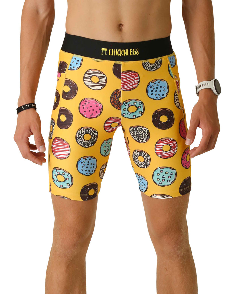 Runner is wearing ChicknLegs in the men's 8 in half tights with pockets in the salty donuts design. The print has fun doughnuts all over it in many flavors on a yellow background.