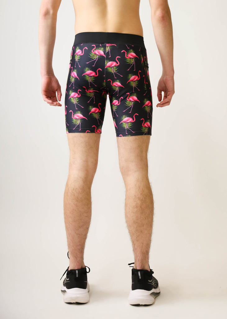 Model is a runner wearing Chicknlegs men's 8 inch half tight with the black flamingo design, facing away from the camera to show the back of the half tights.