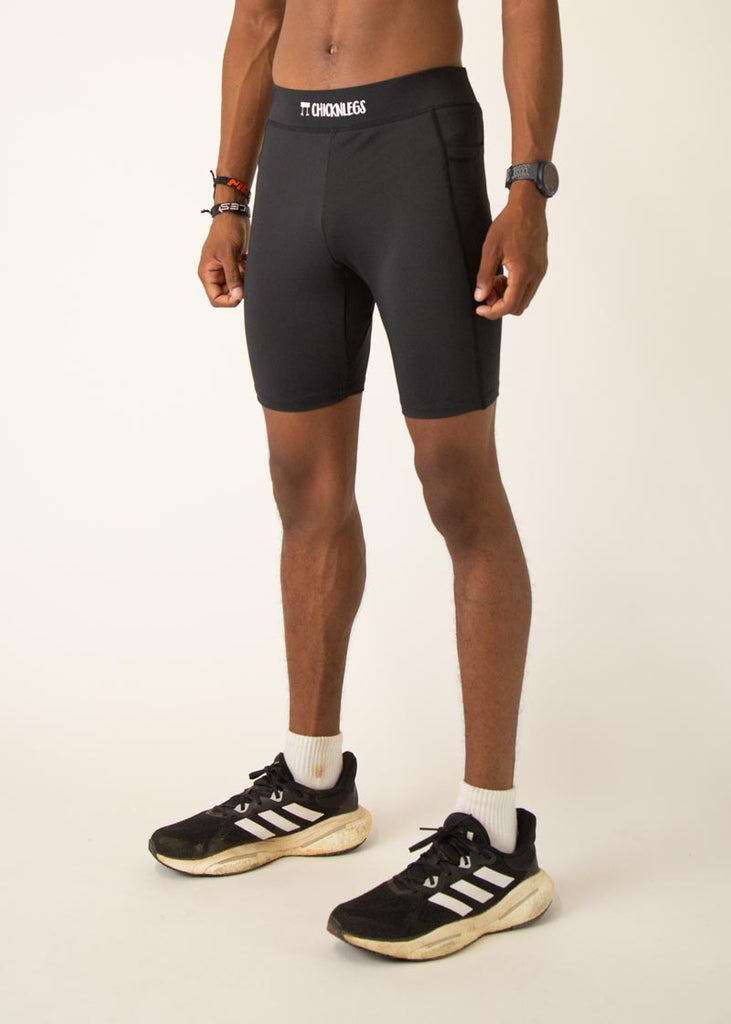 Model wearing Chicknlegs men's 8 inch half tights in the black design, facing left.